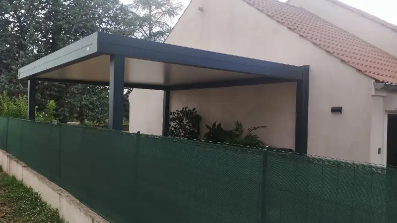Carport aluminium anthracite à toit plat adossé au pignon d’une maison, posé par Créa Habitat Confort