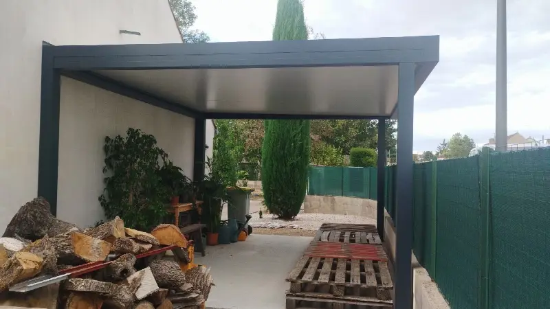 Carport aluminium anthracite adossé à la maison, vu depuis l’allée, avec son plafond clair