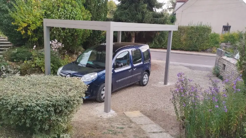 Carport aluminium autoporté au-dessus d'une voiture garée sur du gravier