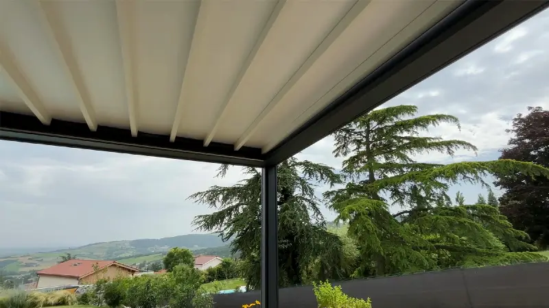 Toile rétractable déployée sous une pergola, vue dégagée sur la campagne