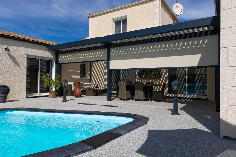 Pergola BIO 120 au bord d'une piscine, stores Zipsun à demi descendus