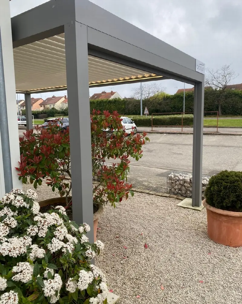 Pergola autoportée gris anthracite posée sur un sol gravillonné