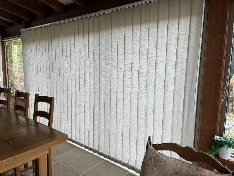 Store à bandes verticales blanc fermé devant une grande baie vitrée