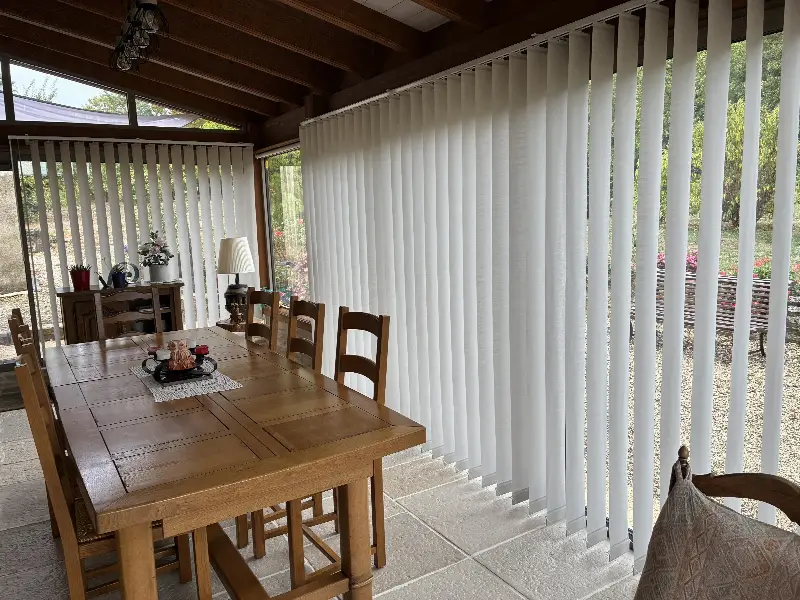Stores à bandes verticales blancs dans une véranda, côté jardin