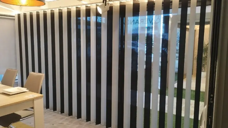 Stores à bandes verticales noires et blanches en alternance devant une grande baie vitrée